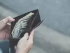 Osoba zaglądająca do swojego portfela