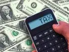 Napis tax na kalkulatorze trzymanym na tle dolarów