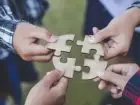 Jakie są formy współpracy - cztery osoby trzymające w dłoniach 4 puzzle, próbujący je dopasować